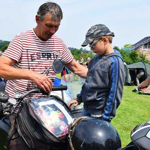 Ein Mann zeigt einem Jungen sein Motorad