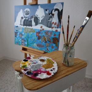 Staffelei mit Farbenpalette und einem Glas mit Pinseln